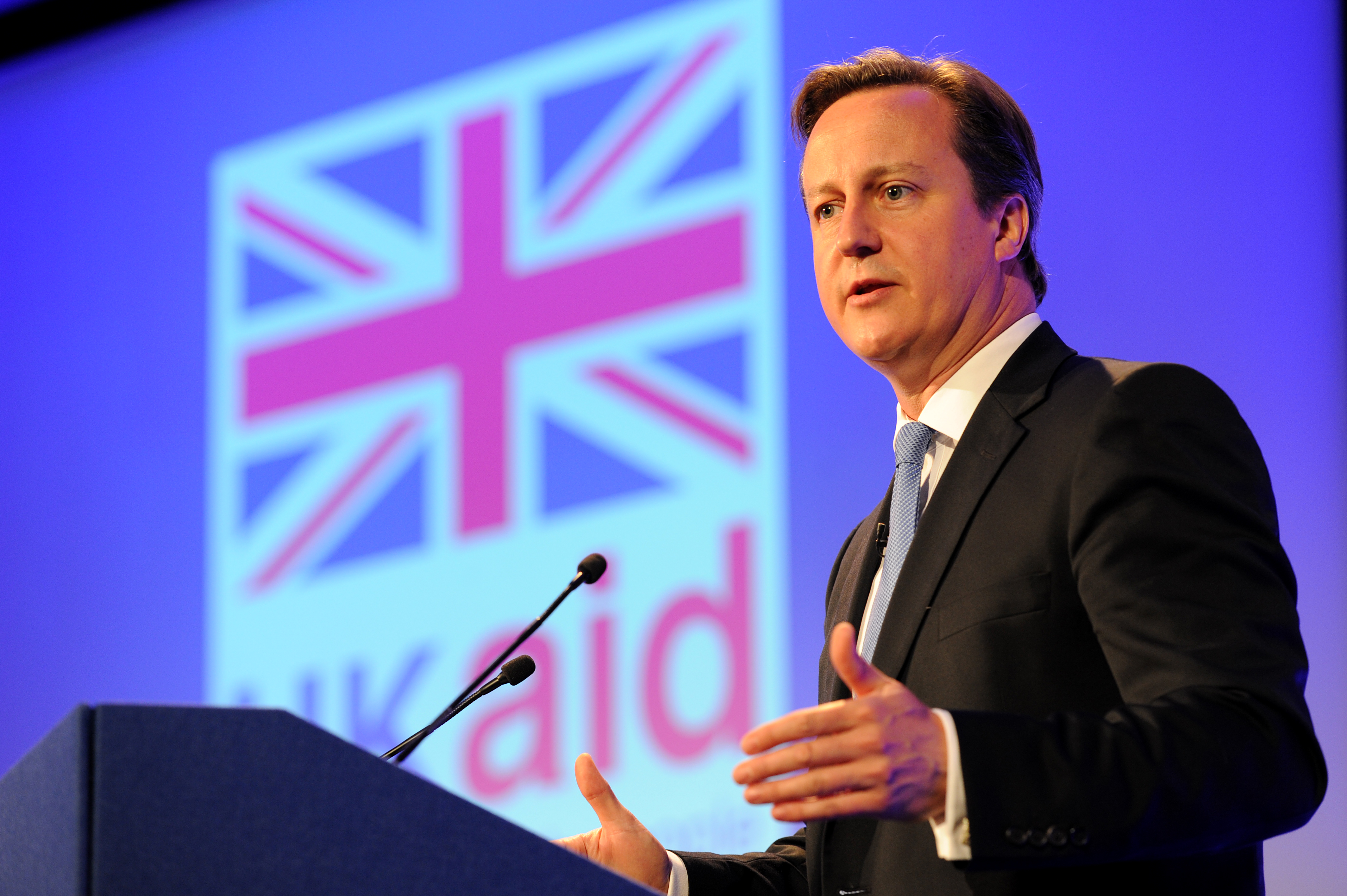 David Cameron at a podium in front of a UK Aid flag