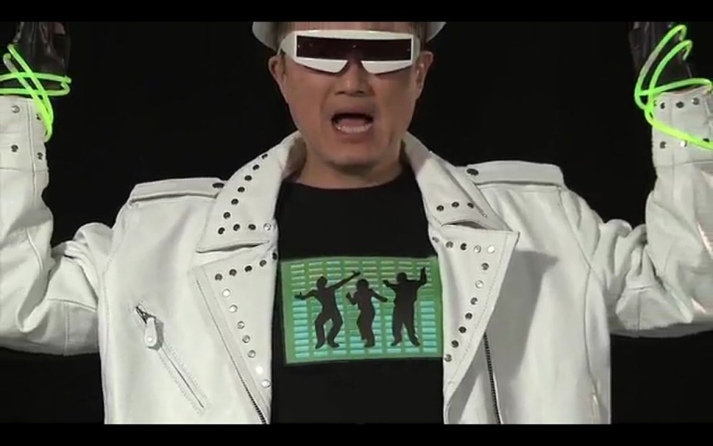 A still from a video showing Jim Kim in a white leather jacket, dancing