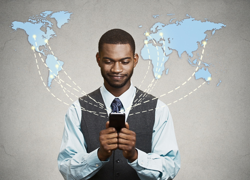 A man with a mobile phone in front of a world map