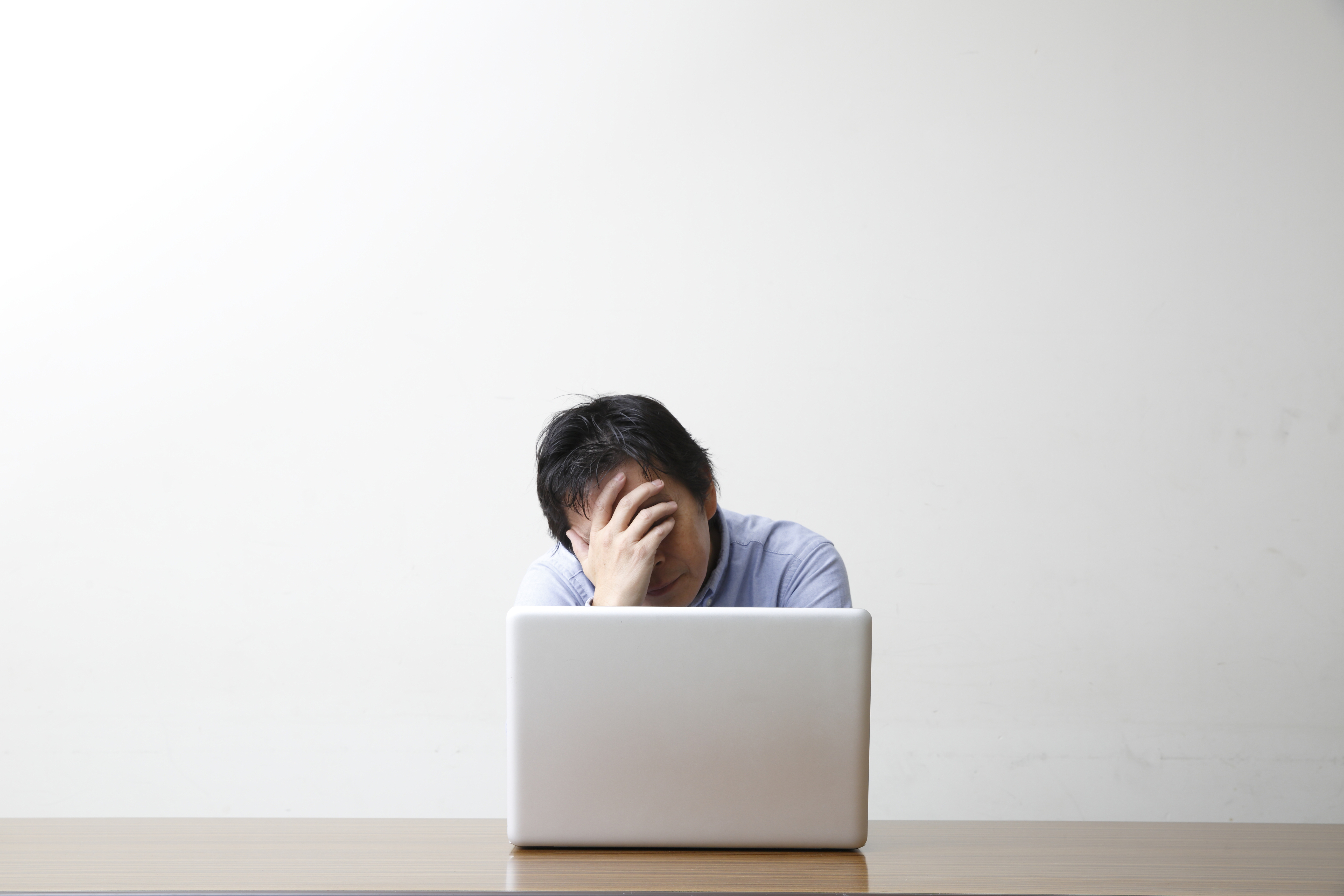 Depressed man by a laptop, white background