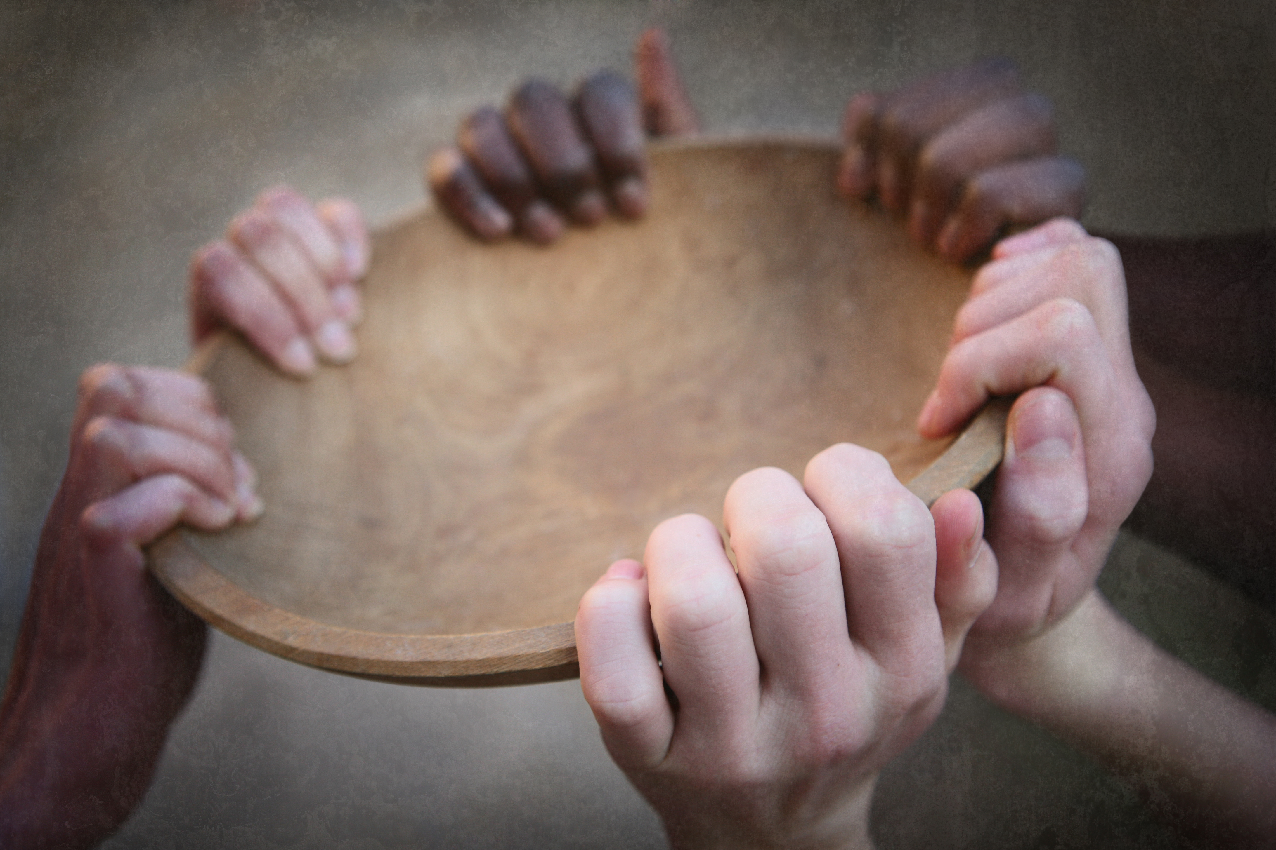 Three pairs of hands holding an empty bowl